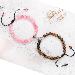 Detail of magnetic stone bracelets for couples with pink and tiger eye beads on white stone