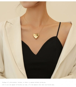 Close-up of a gold heart pendant necklace on a model with a sleek snake bone chain