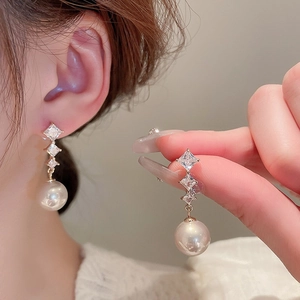 Detailed close-up of French vintage drop earrings with sparkling diamonds and pearls