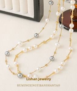 Detail of layered long necklace with white and grey pearls and golden textured metal tubes