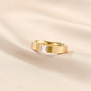Detailed macro view of square-cut zircon set on a matte gold brushed steel ring
