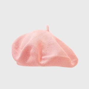 Detail shot of light pink knitted beret showing coarse knit texture and small top tail decoration