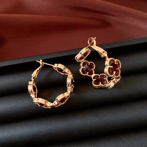 Détail des boucles d'oreilles fleur plaquées or 18k avec pierres rouges sur soie foncée