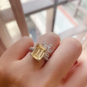 Detail of princess cut yellow gemstone ring with marquise zircon side stones on finger