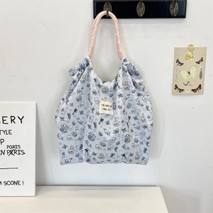 Close-up of quilted light blue canvas tote bag with cartoon cat patterns and rope handles