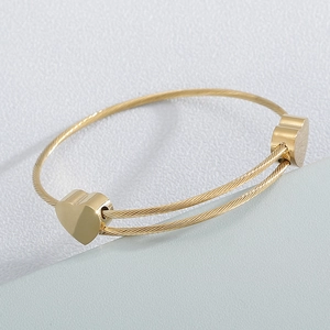 Macro detail of golden stainless steel heart bracelet showing spiral wire texture and polish
