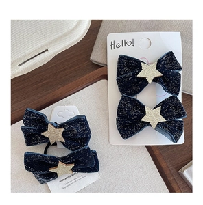 Detailed view of dark blue velvet bow hair clips and ties with silver sparkles and gold stars
