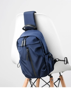 Detail of navy blue nylon crossbody bag with leather handle and multiple zip pockets