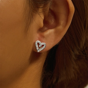 Close-up of heart-shaped S925 sterling silver earrings with inlaid cubic zirconia on ear