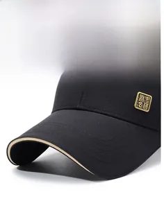 Detail of a black baseball cap featuring a stiff brim and a gold metallic badge accent