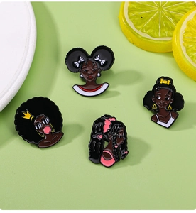 Detailed flat lay of four colorful cartoon black girl pins on a green surface
