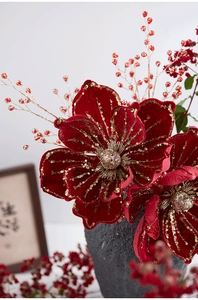 Detailed view of red velvet Christmas flowers with gold glitter edges in a ceramic vase