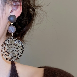 Detail of model wearing leopard print resin hoop earrings with brown concentric rings