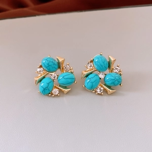 Detailed view of vintage gold earrings featuring blue textured stones and clear zircons