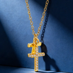 Macro view of gold double cross pendant with sparkling zircon inlays on fine O-chain