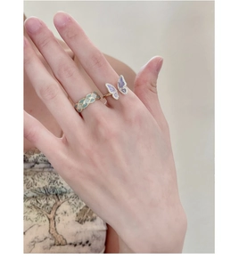 Detail of vintage rings with purple butterfly and green enamel patterns on model fingers