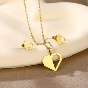 Detail of gold geometric heart necklace and earrings set on a white tray