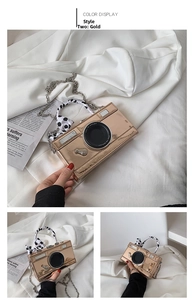 Detail of rose gold camera-shaped mini bag with chain strap and polka dot ribbon handle