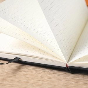 Classic cloth cover bullet dotted journal notebook with ivory dot grid paper on a wood desk