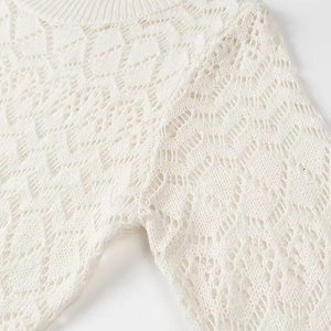 Close-up of white knit set showing hollow-out texture and ribbed neckline detail