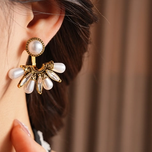 Detail view of vintage fan-shaped earrings with pearls and crystals worn on ear