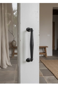 Detail of vintage cast iron door handle with black hammered texture on a white frame