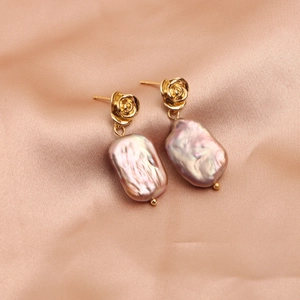 Detailed macro view of vintage gold rose studs with iridescent baroque pearl pendants