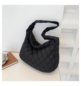 Detailed view of black quilted cloud bag showing the puffy nylon texture and shoulder strap