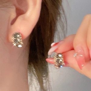 Macro shot of gold star butterfly stud earrings with zircon inlay showing glitter effect
