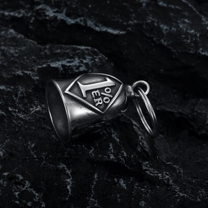 Macro shot of 1% ER engraved vintage motorcycle bell pendant on black rock surface