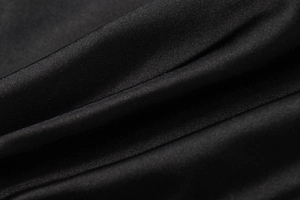 Detailed macro view of black satin fabric showing smooth texture and elegant draped folds