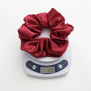 Macro shot showing the lightweight 12.6g burgundy satin scrunchie on a scale