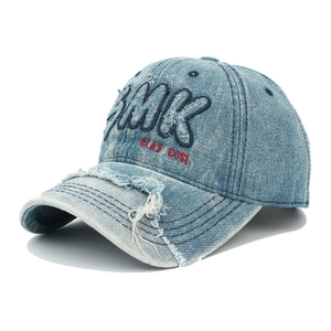 Détail de casquette en denim bleu avec broderie BMK et bord de visière effiloché vintage