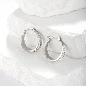 Macro detail of silver stainless steel hoop earrings with double-row crystals on white stones