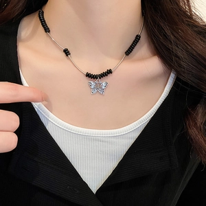 Detail of beaded necklace with butterfly pendant and metallic tubes on model neck