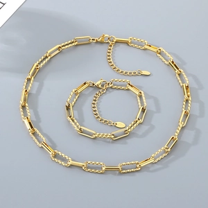 Detailed view of golden paperclip chain necklace and bracelet set with twisted link accents