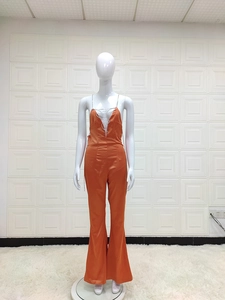 Detail of orange satin jumpsuit featuring rhinestone chain straps and deep V-neckline