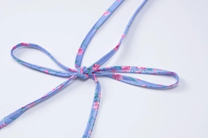 Detailed macro view of a light blue floral halter strap tied into a bow on a midi dress