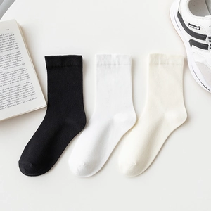 Three pairs of cotton crew socks in black white and beige shown with a stylish sneaker