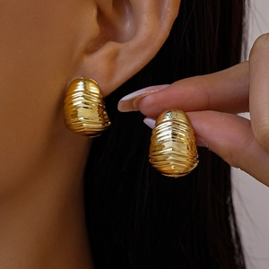 Gros plan de boucles d'oreilles goutte dorées avec texture métallique sur un mannequin