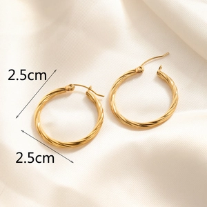 Detailed macro view of 2.5cm golden twist hoop earrings on elegant silk fabric