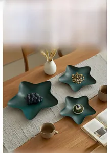 Detailed view of nested dark green star-shaped iron trays with a matte finish decor