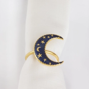 Golden moon napkin ring with deep blue enamel and star details on white linen cloth