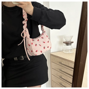 Detail of pink corduroy shoulder bag with strawberry embroidery in a casual home setting