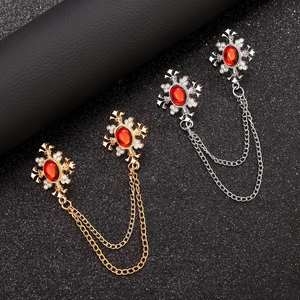 Detail of vintage gold and silver collar pins with red gemstones and double metal chains
