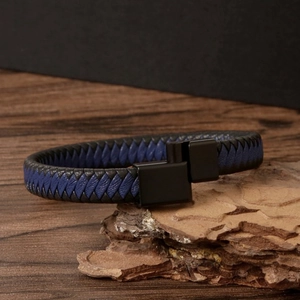 Minimalist men's braided leather bracelet with black magnetic clasp on natural wood background