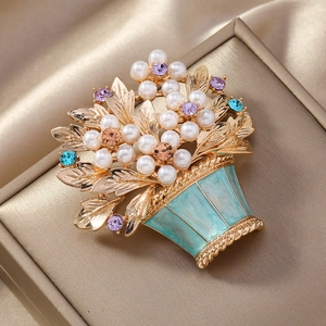 Macro detail of enamel flower basket brooch with pearls and colorful rhinestones