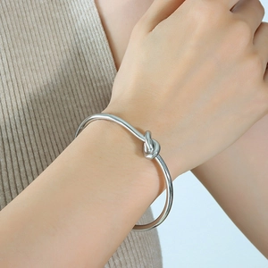 Bracciale rigido d'argento con nodo dal design minimalista al polso di una donna