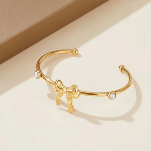 Adjustable golden stainless steel cuff bracelet with bow design and faux pearls