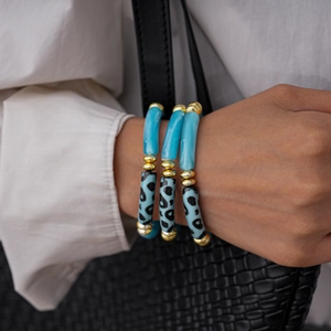 Close-up of three-piece blue acrylic leopard print elastic bracelets with gold beads